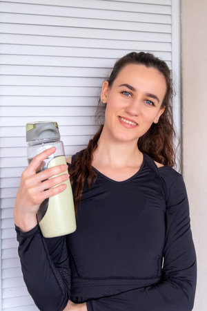 Slender sporty girl woman in sportswear drinking water, resting after fitness exercises.