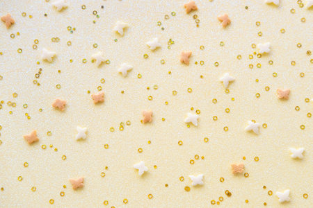 Easter pattern made of white and yellow butterflies and confetty on a yellow background.