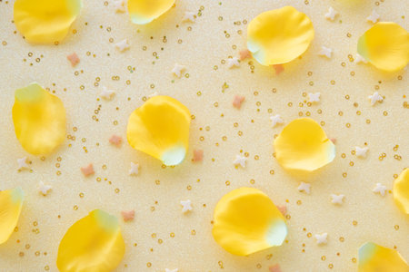 Yellow rose petals and confetti on yellow background. Flowers composition.