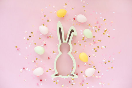 Easter decoration with bunny eggs and confetti on pink background.の写真素材