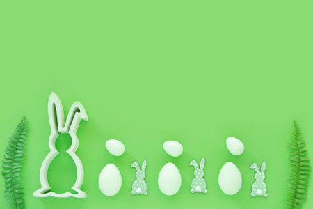 Easter eggs with wood rabbits, green leaves on green background. Egg hunting.の写真素材
