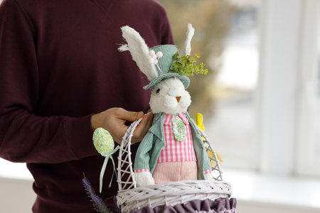 Easter toys. Easter basket with a decorative rabbit in the hands of a man. Blurred background, copy space.の写真素材