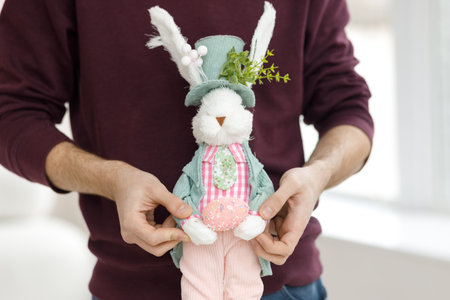 Easter toys. Easter basket with a decorative rabbit in the hands of a man. Blurred background, copy space.の写真素材