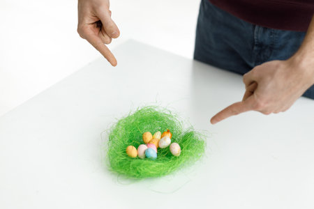 Easter toys. Easter toys with green leaves in the hands of a man. white background. Chicken eggs, twigs with green leaves on the hay. Easter holiday concept background.の写真素材