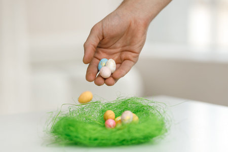 Easter toys. Easter toys with green leaves in the hands of a man. Blurred background. Chicken eggs,...