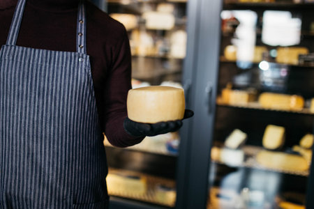 A man holds in hands cheese at the cheese factory.の写真素材