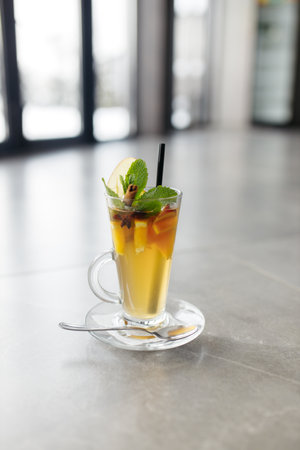 Mulled wine in a glass mug, hot red wine with orange and apple, spices with cinnamon, pouring into a glass. Beautiful gray background. copyspace.の写真素材