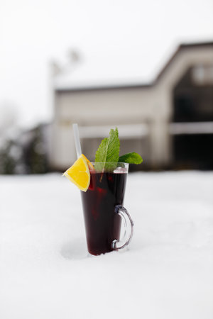 Mulled wine in a glass mug, hot red wine with orange and apple, spices with cinnamon, pouring into a glass on a table. beautiful backgroundの写真素材
