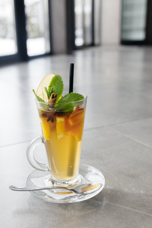 Mulled wine in a glass mug, hot red wine with orange and apple, spices with cinnamon, pouring into a glass. Beautiful gray background. copyspace.の写真素材