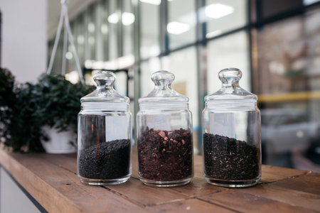 Loose tea in glass jars. Green tea with hibiscus and wild rose, chamomile in glass jars on table.
