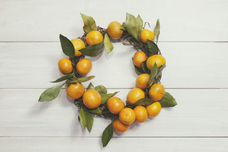 Wreath of mandarins (tangerines) on white wooden backgroundの写真素材