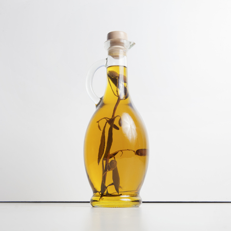 Olive oil in a glass jug with an olive branch insideの写真素材