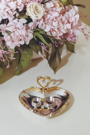 Wedding rings on a saucer in the shape of a heartの写真素材