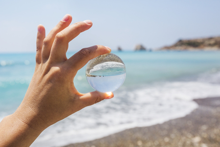 Glass ball in hand on Seascape backgroundの写真素材