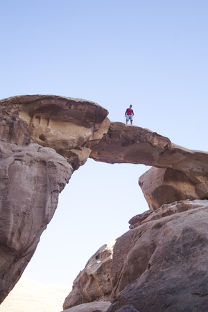 Tourist on a rock in Wadi Ram desert. Stone bridge arch. Jordan landmarkの写真素材