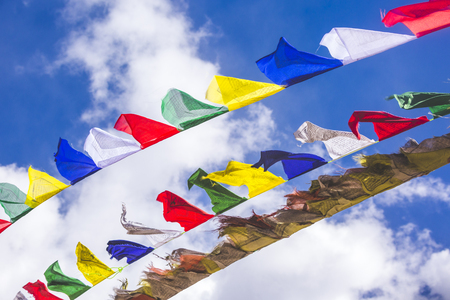 Multicolored Buddhist flags on a background of blue skyの写真素材