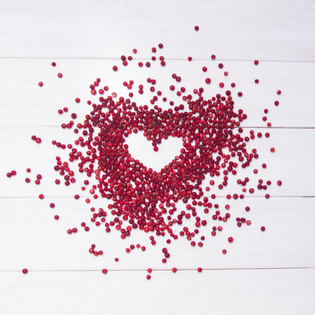 Round heart shape frame of red cranberries on a white wooden backgroundの写真素材
