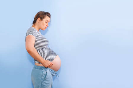 Pregnant woman on a blue wall backgroundの写真素材