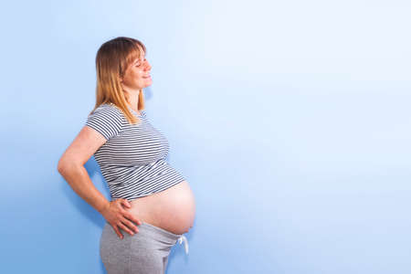 Pregnant woman on a blue wall backgroundの写真素材