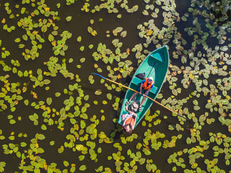A couple swims on a boat on a pond with water lilies. View from aboveの写真素材