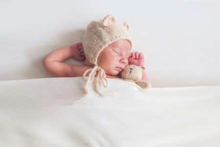 Newborn baby with teddy bear sleeps on white backgroundの写真素材