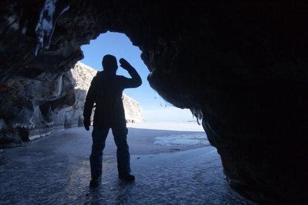 Silhouette of a man at the entrance to the cave. Winter Baikal, Russia