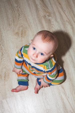 Eight month old baby boy sitting on the floor, top view