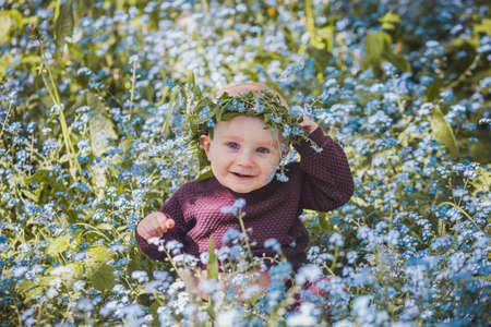 A nine month old boy wearing a wreath of forget-me-nots in a clearingの写真素材