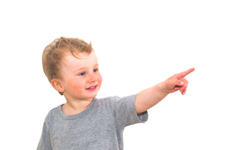 One and half year smiling boy pointing a finger at something on white backgroundの写真素材