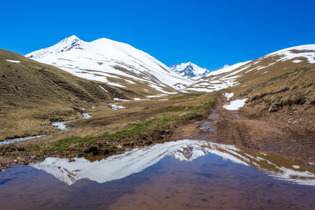 Mountains reflection in a puddle. Caucasian landscape. Karachay-Cherkessia, Russia