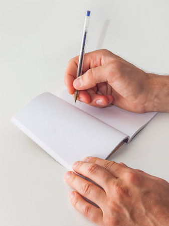 Male hands with a pen write in an empty notebookの写真素材