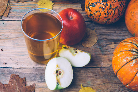 Cold apple cider or apple juice with fresh apples on a wooden background. Autumn drinks. Autumn mood.の写真素材