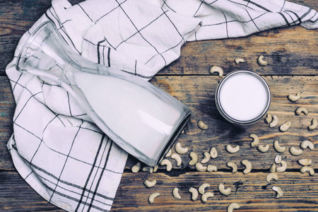Fresh organic raw vegan cashew milk with cashew nuts on wodden background.の写真素材