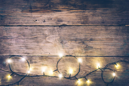 Christmas lights frame. Christmas wooden rustic background with (decorated) christmas lights. Copy space. Top view. Christmas mood, comfort.の写真素材