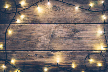 Christmas lights frame. Christmas wooden rustic background with (decorated) christmas lights. Copy space. Top view. Christmas mood, comfortの写真素材