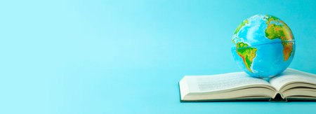 Earth globe on an open book on a blue banner background. Knowledge, learning, study concept....
