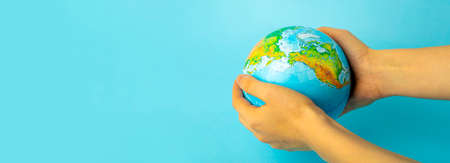 Earth globe in hands on a clean blue background. The concept of protecting nature, ecology and global peaceの写真素材