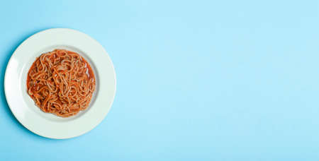 Spaghetti pasta with tomato sauce on a white plate on a blue empty background. Italian pasta dish background. Italian cuisine and foodの写真素材