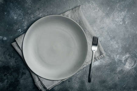 Gray empty plate ceramic with fork on gray stone background. Gray minimalism concept. Copy space.の写真素材