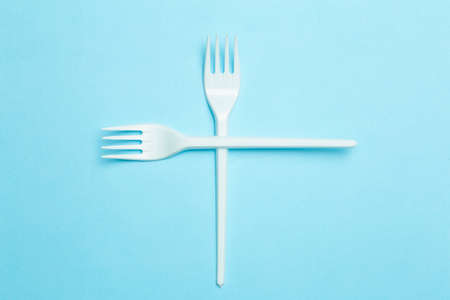 Plastic forks on a blue background. Plastic waste and pollution conceptの写真素材