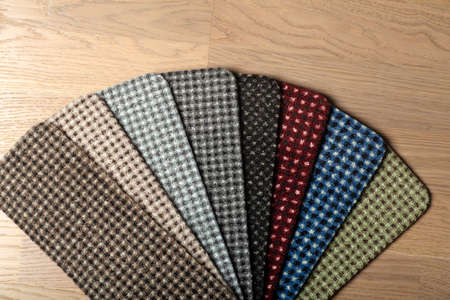 Types and samples of carpets in different colors on wooden floor backgrond. Carpets for rooms, apartments and houses.の写真素材