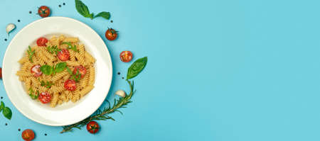 Food pasta on a blue background. Italian fusilli pasta with tomatoes, herbs and basil on a white plate. Healthy food concept.の写真素材