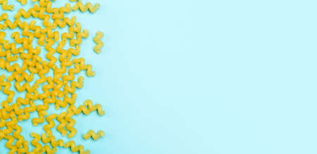 Pasta on blue banner background. Raw Italian vermicelli spiral pasta. Food background.の写真素材