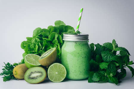 Green detox healthy smoothie from green fruit - avocado, salad, kale, lime, kiwi, mint. Alkaline diet concept. Vegan healthy alkaline food. Green fruit background. Flat layの写真素材