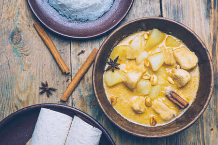 Massaman curry (chicken curry) whith cinnamon sticks and plane riÑe on wooden background. Coconut milk curry.の写真素材