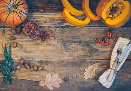 Autumn background (dinner table) from fallen leaves, punpkin and knife and fork on old rustic wooden table. Thanksgiving day concept. Top view. Copy spaceの写真素材