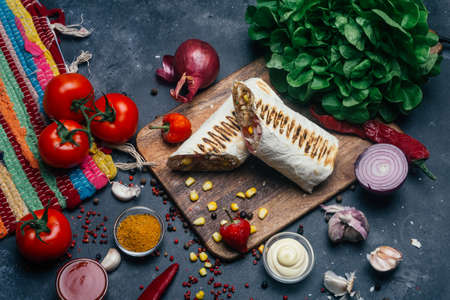 Burritos wraps with grilled meat and vegetables - peppers, tomatoes and corn. Mexican foodの写真素材