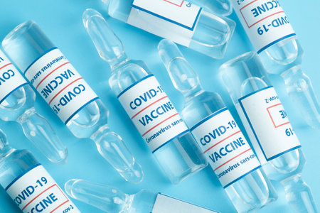 Vaccine against COVID-19. Glass medical vials with liquid. Ampoules with coronavirus vaccine on a medical glass tableの写真素材