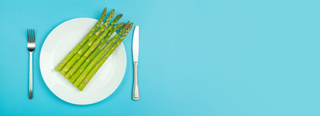 Asparagus on a white plate on a blue banner background. Fresh vegetable asparagus for a healthy diet...