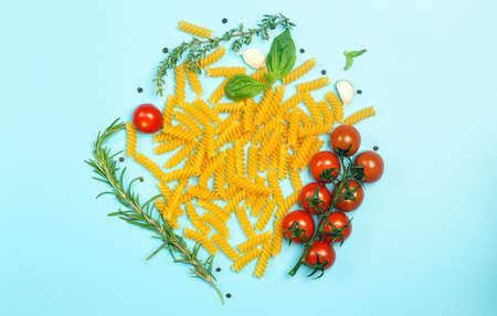 Raw fusilli pasta with tomatoes, herbs and basil. Italian pasta with ingredients in the colors of the Italian flag.の写真素材